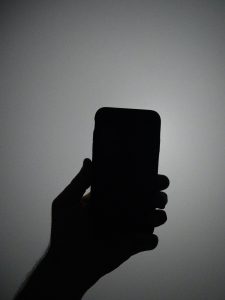 Hand holding mobile phone in shadow
